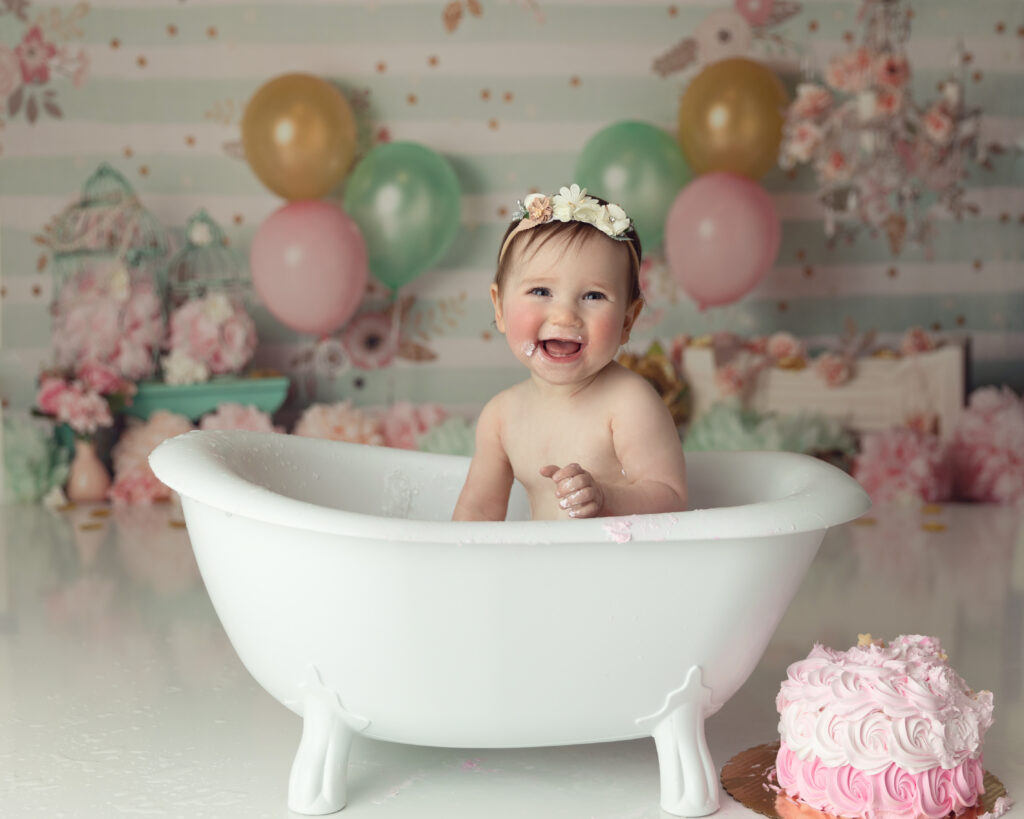 1st Birthday girl in mini tub splashing around after her cake smash.