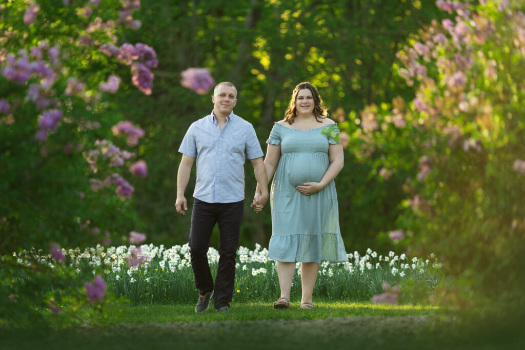 Expecting mother & father-to-be waking through a garden.