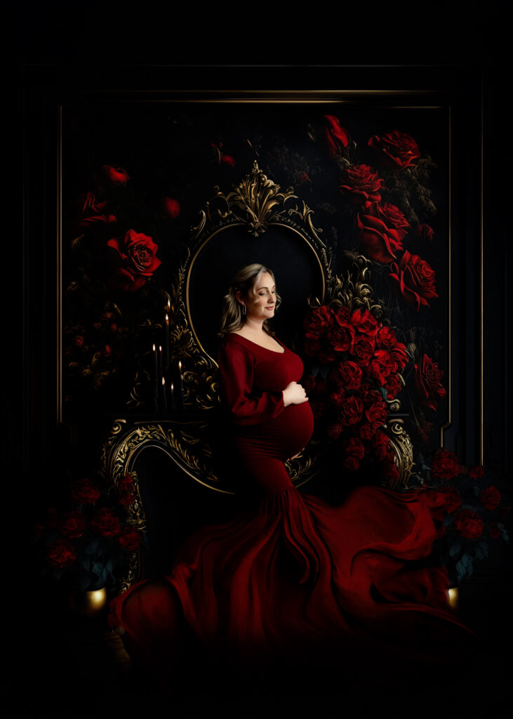 Pregnant mother in a red elegant gown with roses on a black & gold background.