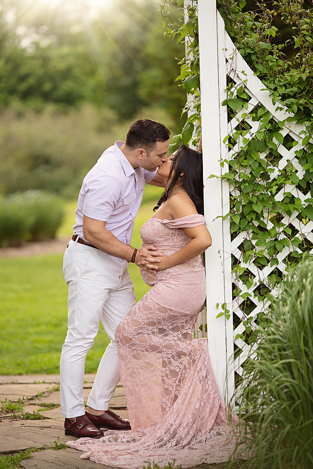 Fist time pregnant mother & gather to be kissing in a garden.