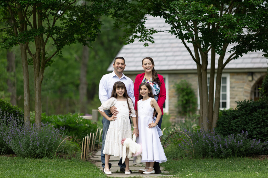 sister in communion dress posing for a family photo with mom & day in a local par
