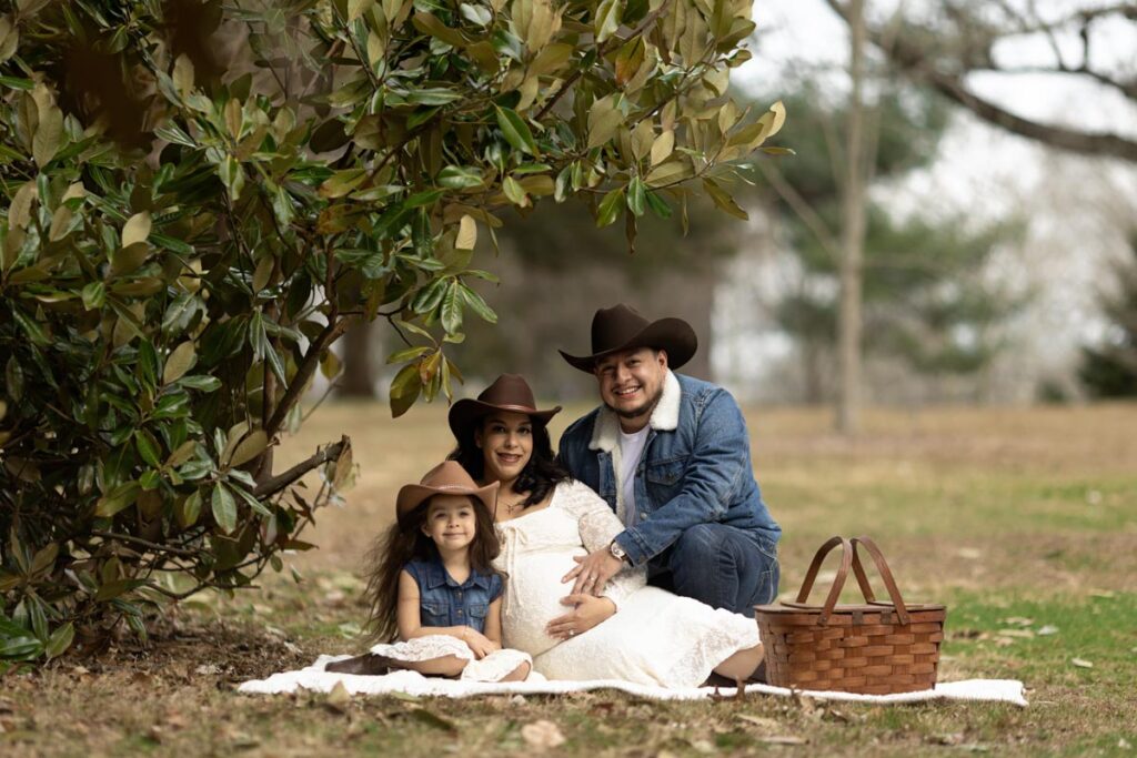 expecting mom, with soon to bed dad & little sister sitting on a picnic blanket in colonial park in somerset, NJ