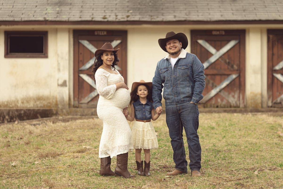expecting mother to be holding hand with her young daughter in the middle holding hands with dad