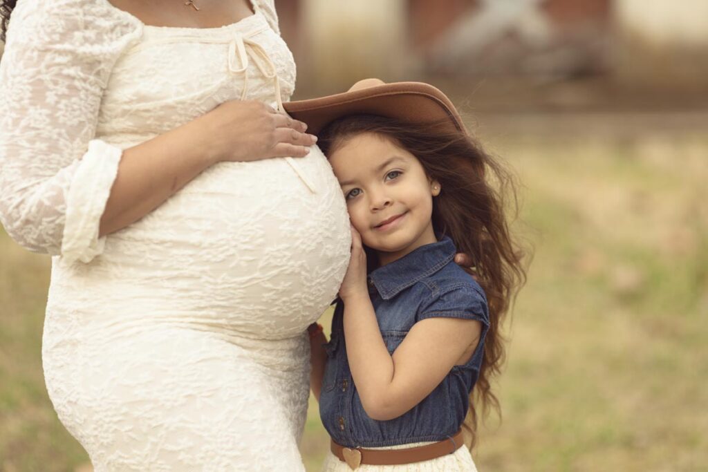 soon to be big sister hugging expecting mom's belly